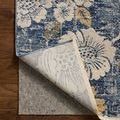 Corner of rug flipped back revealing woven backside and protective rug pad underneath