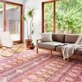 Layla Magenta Multi Rug styled in a bright living room with modern chair, sofa, plants, and large windows