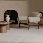 Side view of chair styled indoors near beige fireplace and wooden furniture