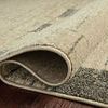 Rolled edge view revealing thickness and tight woven backing of taupe patterned rug