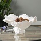 White textured bowl with an organic coral-like shape holding decorative brown wicker spheres on a glass table