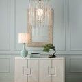 Pendant suspended above white cabinet with large textured frame mirror and ceramic table lamp