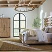 Side angle of bed in spacious room with vaulted ceiling featuring windowed cabinet and natural fiber rug