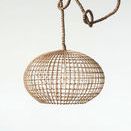 Pendant light hanging against plain light background from braided cord with loops above shade