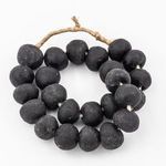 Curved line of black sea glass beads with texture variations and tied natural fiber cord