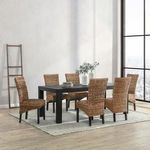 Black dining table styled in a bright room with woven stick-back chairs on a rug