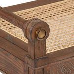 Close-up of Vienna Bench corner showing carved wood frame, handwoven cane seat, and brass circular accent