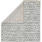 Back of rug folded over showing reverse linear pattern and fringed edge
