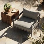 Outdoor setting showing chair on stone patio next to wooden side table with plant and notebook