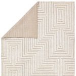 Rug corner folded over showing solid taupe wool backing contrasting with patterned cream front
