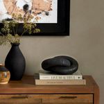 Reclaimed wood knot sculpture styled on stacked books with a black vase and wall art in the background