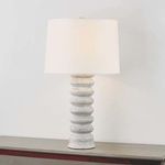 Harwinton Table Lamp shown on a wooden surface against a light wall, illuminated to highlight texture and form