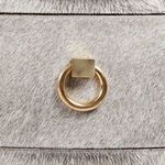 Close-up detail of round gold drawer pull with square mounting on light faux fur drawer front