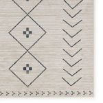 Close-up of a corner on the cream and dark slate rug highlighting tribal diamond and arrow designs