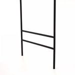 Detail of bottom portion of black metal support frame showing two horizontal bars above floor level