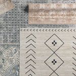 Multiple rugs including the Milea Trellis tan and cream rug layered on floor among blue and cream rugs