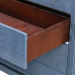 Side view of an open drawer with wood interior on navy blue textured dresser.