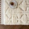 Close-up of plush shag texture and detailed pattern with tasseled fringe along wooden floor