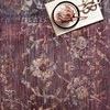 Close-up of grape-colored rug showing detailed floral patterns with a book and flower placed on top
