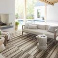Rug shown in outdoor patio setting under a beige sofa and side table