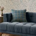 Earl pillow displayed on a blue velvet tufted bench with leaf patterned wallpaper backdrop