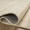 Chris Natural Sage Rug partially rolled to reveal dark underside backing and wool pile texture