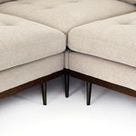 Close-up of sectional corner joint featuring wooden base and tapered legs