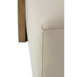 Close-up of rounded ottoman corner with beige leather upholstery adjacent to oak wood side table