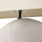 Metal lamp rod connecting the dimpled ceramic base to elongated cream fabric shade