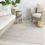 Light gray area rug styled in a modern outdoor seating area with wicker furniture and decorative pillows