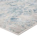 Close-up of textured high-low pile and detailed edging on mottled blue and gray area rug