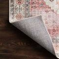 Skye Ivory Berry rug corner flipped up showing non-slip backing texture on dark wood flooring
