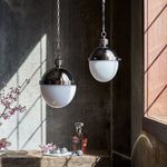 Two Otis Pendant Small lights hanging in rustic room with sunlight and décor on wooden surface below