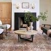 Zoomed out living room shot showing full rug under furniture centered with black metal frame chairs