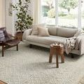Noelle Ivory / Blue Rug styled in bright living room under gray sofa and wooden side table