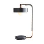 Lamp in side profile with bulb lit inside the black drum shade
