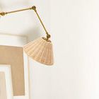 Wall sconce mounted beside framed artwork casting light downward on plain wall