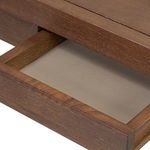 Open drawer lined with beige leather beneath oak tabletop edge