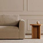 Close-up of right armrest and plush cushion with subtle piping next to wooden side table