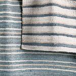 Back side of Del Mar rug showing reverse weave with blue and cream striped pattern and natural jute texture