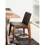 Deco Dining Chair styled beside table with decorative books and natural light through large window.