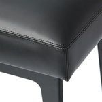Close-up of stool’s black leather upholstery corner showing detailed stitching