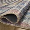 Rolled edge of rug lifted to show backing and plush pile on wood floor
