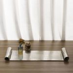 Indoor setting with industrial scroll tray on wood surface holding small vase and lit candle