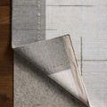 Backside of rug corner lifted revealing woven backing and underside texture with edging detail