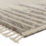 Close-up of braided fringe and wool texture in cream and taupe tones on rug corner