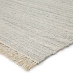 Handwoven Torre area rug in light gray and cream with soft texture and fringed edges