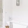 smoked glass pendant hanging above freestanding white bathtub in bright minimalist bathroom