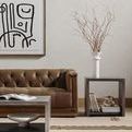 Living room styled scene showing the coffee table centered in front of tufted brown leather sofa with art