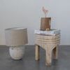 Solano Carved Stool used as side table next to lamp on gray floor and blue wall